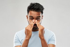 Man with nasal congestion touching the bridge of his nose