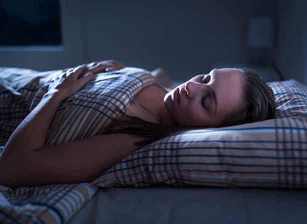 Woman sleeping on her back which is a risk factor for sleep apnea in Eugene