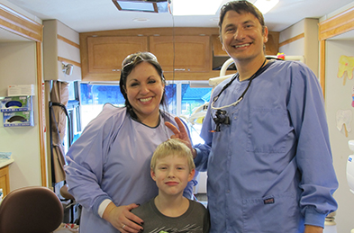 Dentist and team member smiling with young patient
