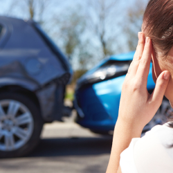 Tired woman looking at aftermath of minor car accident