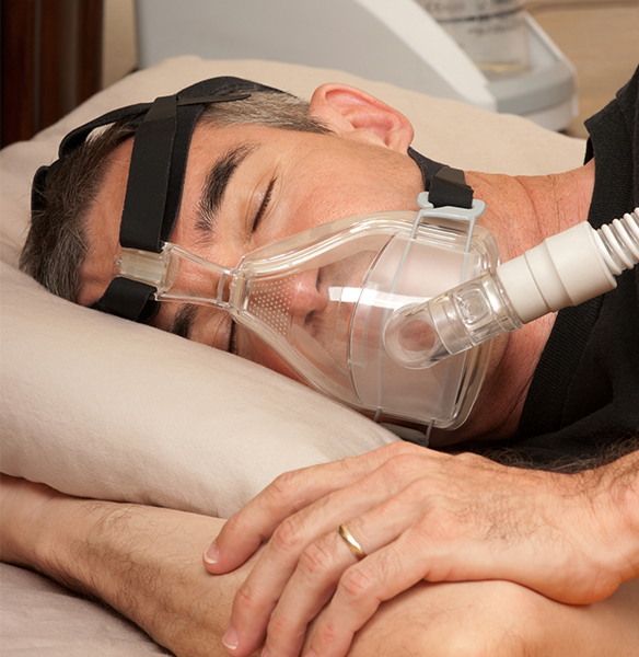 Man sleeping while wearing a C P A P system