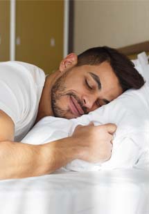 Man in need of sleep apnea therapy staring at alarm clock