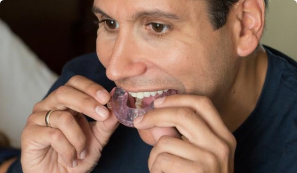 Man placing purple sleep apnea oral appliance in his mouth
