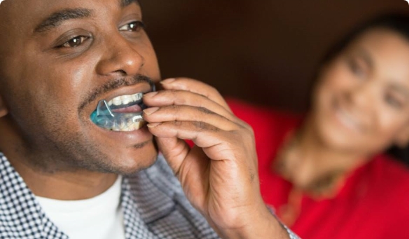 Man placing blue sleep apnea oral appliance in his mouth