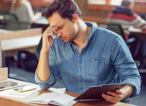 Man in denim shirt falling asleep at desk due to sleep apnea in Eugene