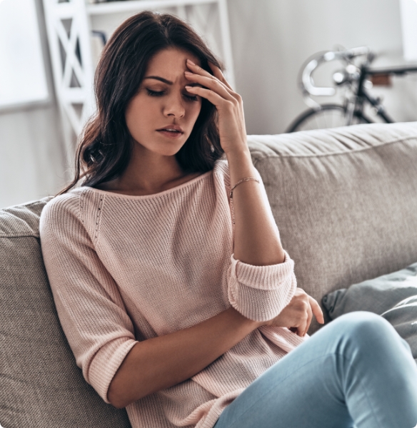 Frustrated woman touching her temple while sitting on couch