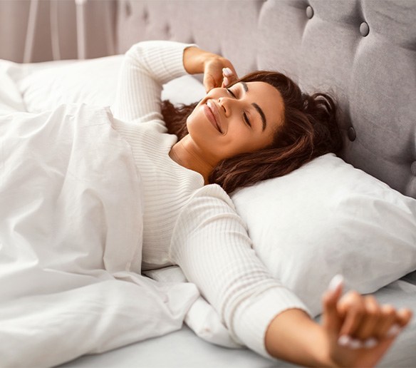 Woman stretching in bed after good night of sleep