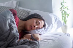 Woman sleeping under a gray weighted blanket 