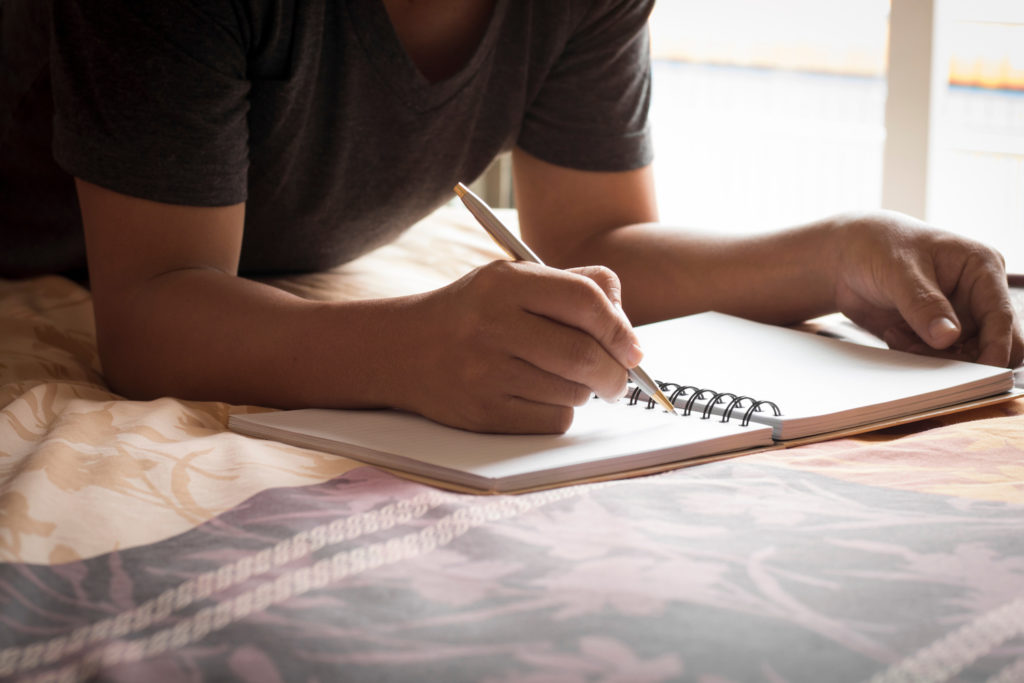 writing on notebook in bed