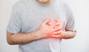 Man holding hand over heart in discomfort