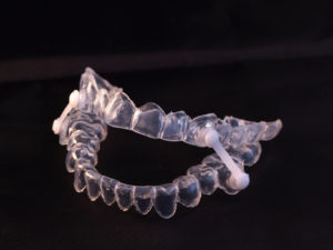 Oral appliance to relieve sleep apnea symptoms on dark background