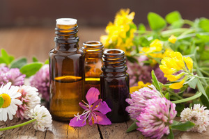 Bottles containing essential oils surrounded by flowers